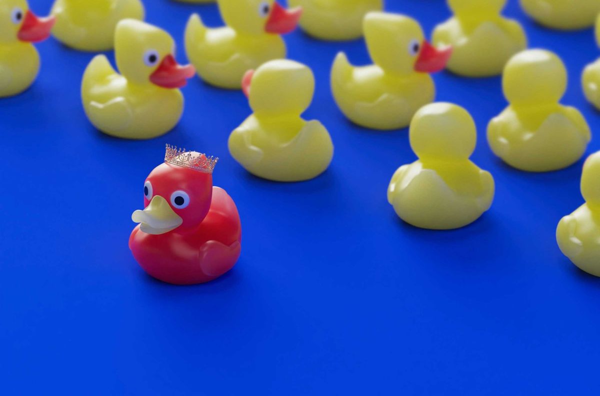 a bunch of rubber ducks sitting on a blue surface with a red one