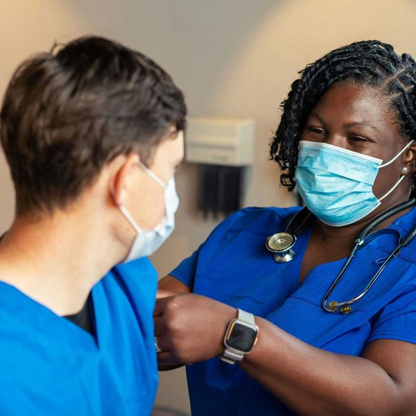 A travel nurse gives another nurse a vaccination