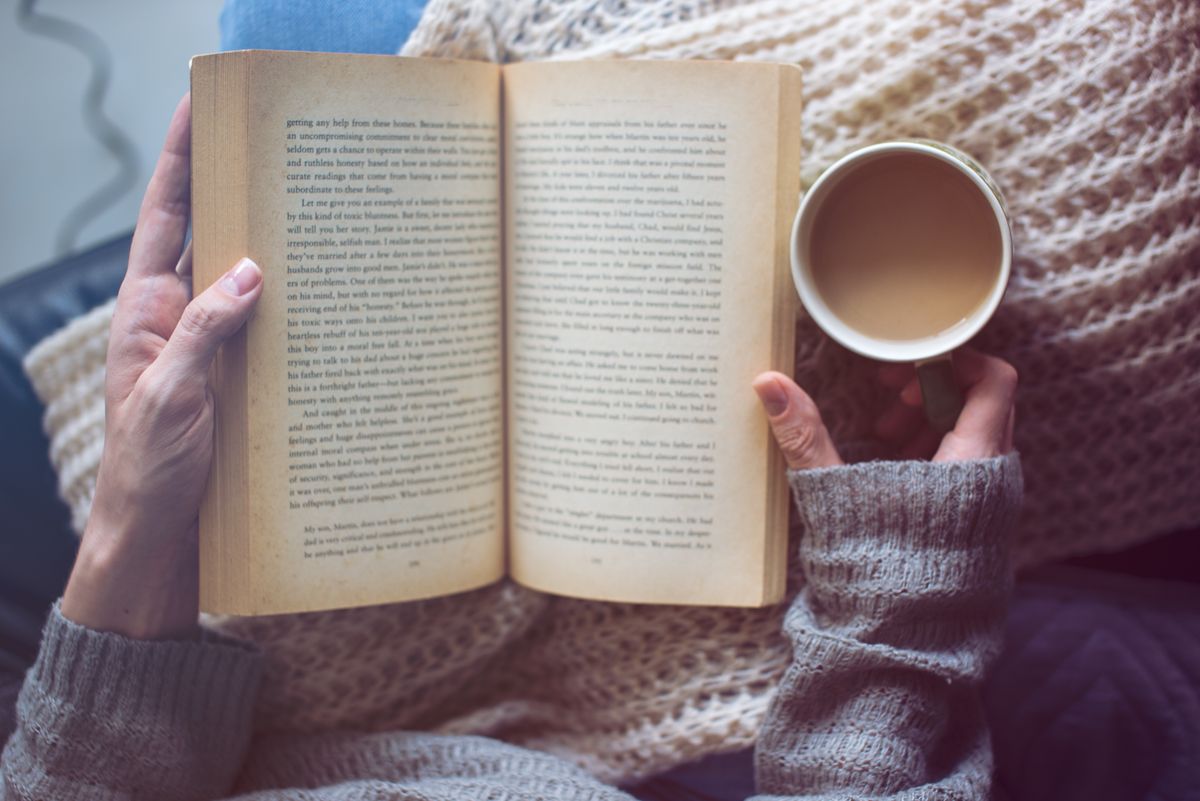A woman reading a business book and holding coffee