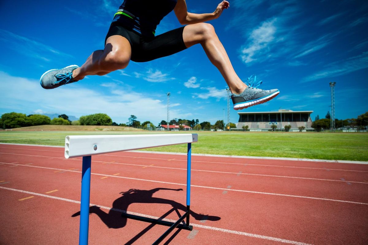 athlete jumping hurdle
