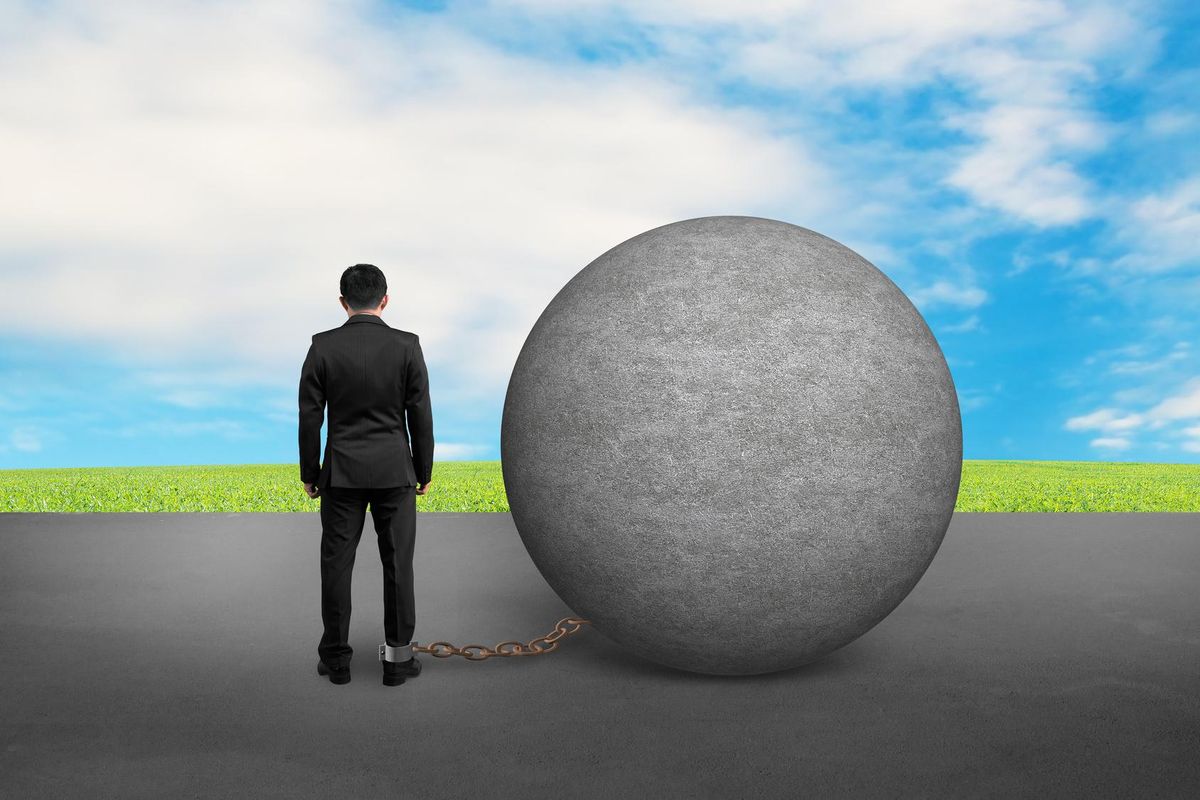 business man being trapped with concrete ball