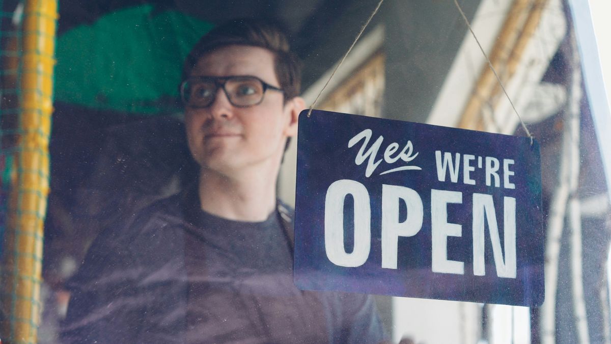 Business owner with an open sign in shop window