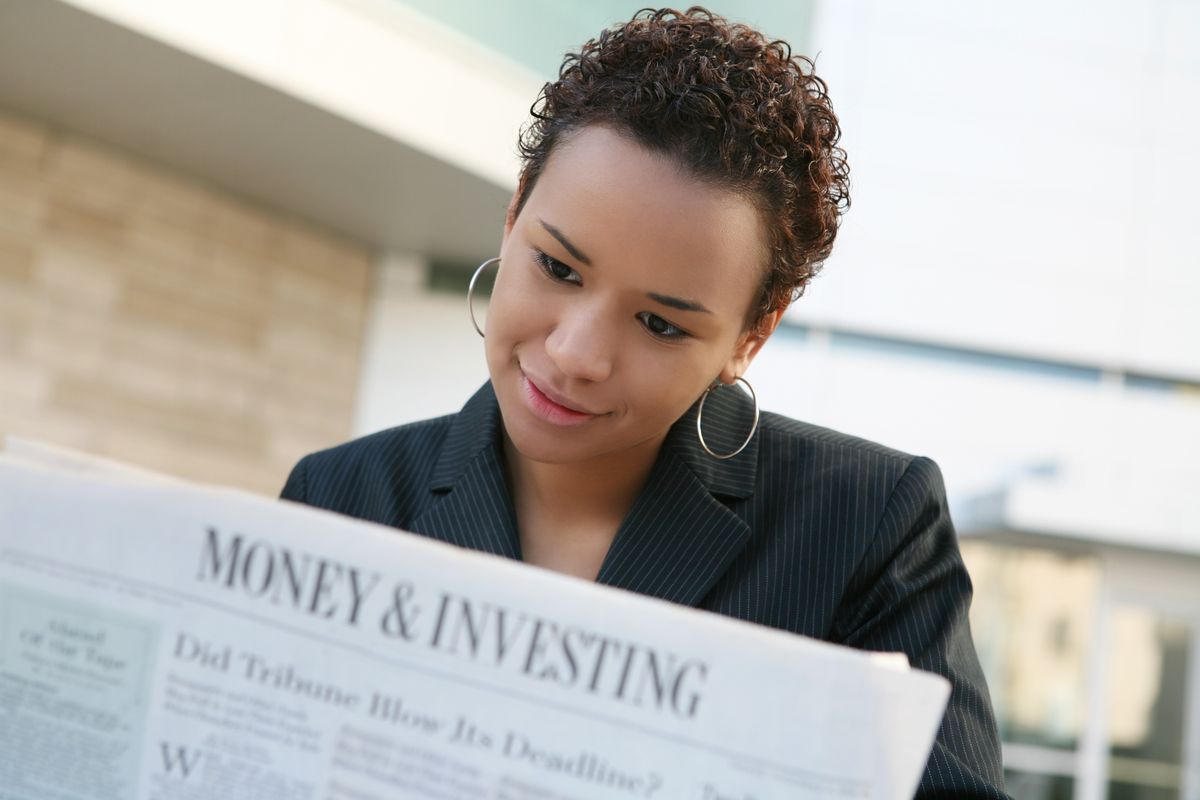 Business woman reading newspaper before investing