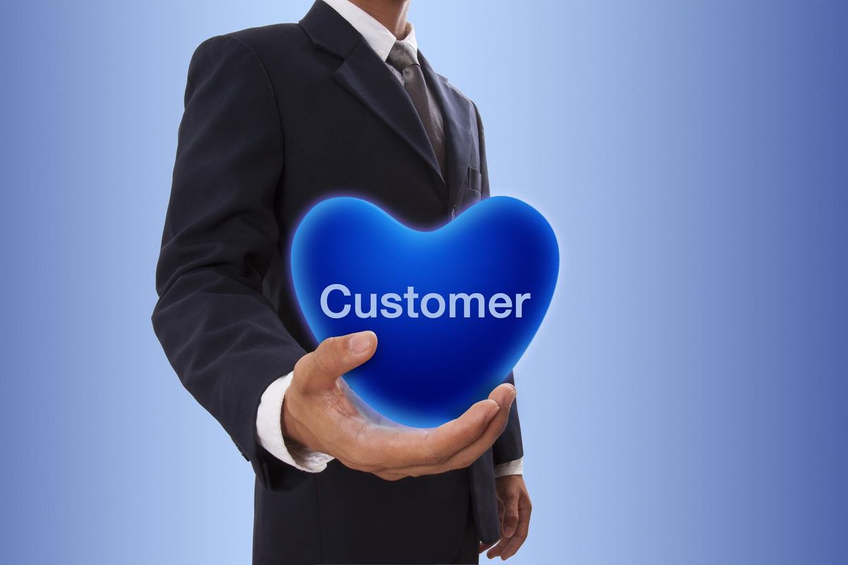 Businessman hand holding blue heart bubble with customer word