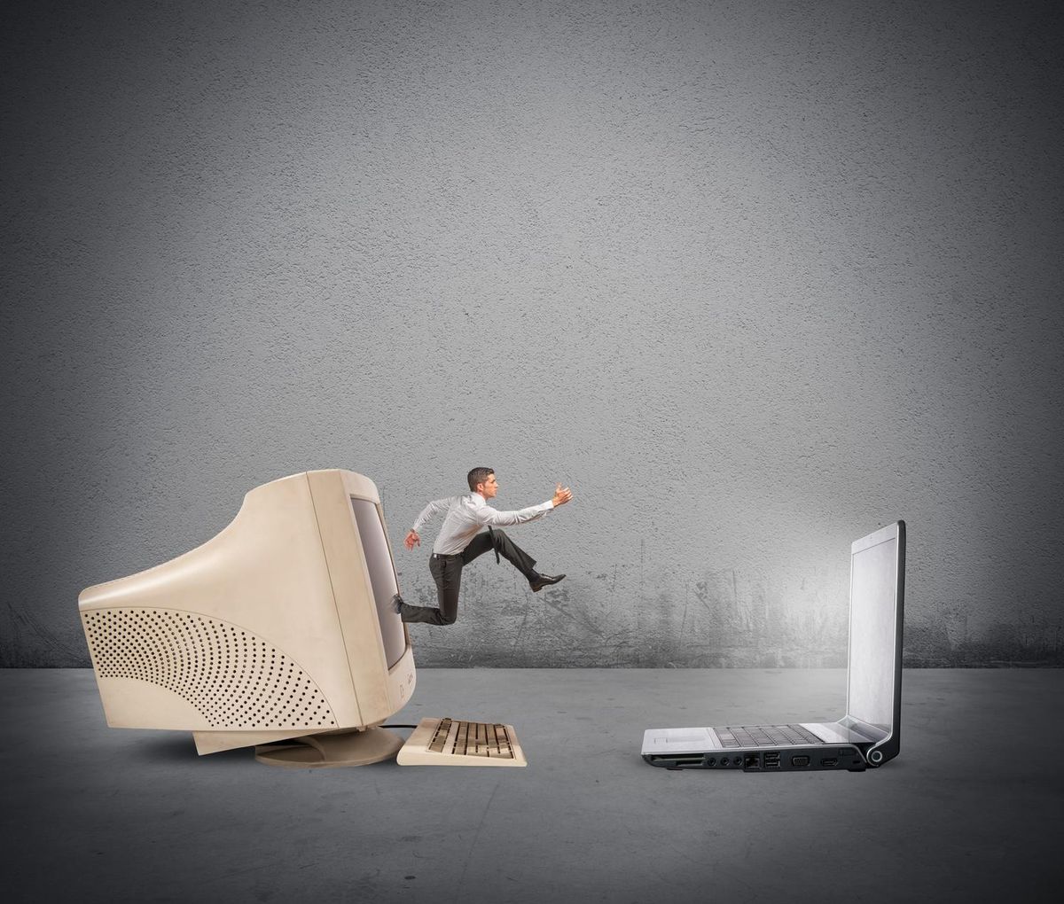 Businessman jumping from old computer to new laptop