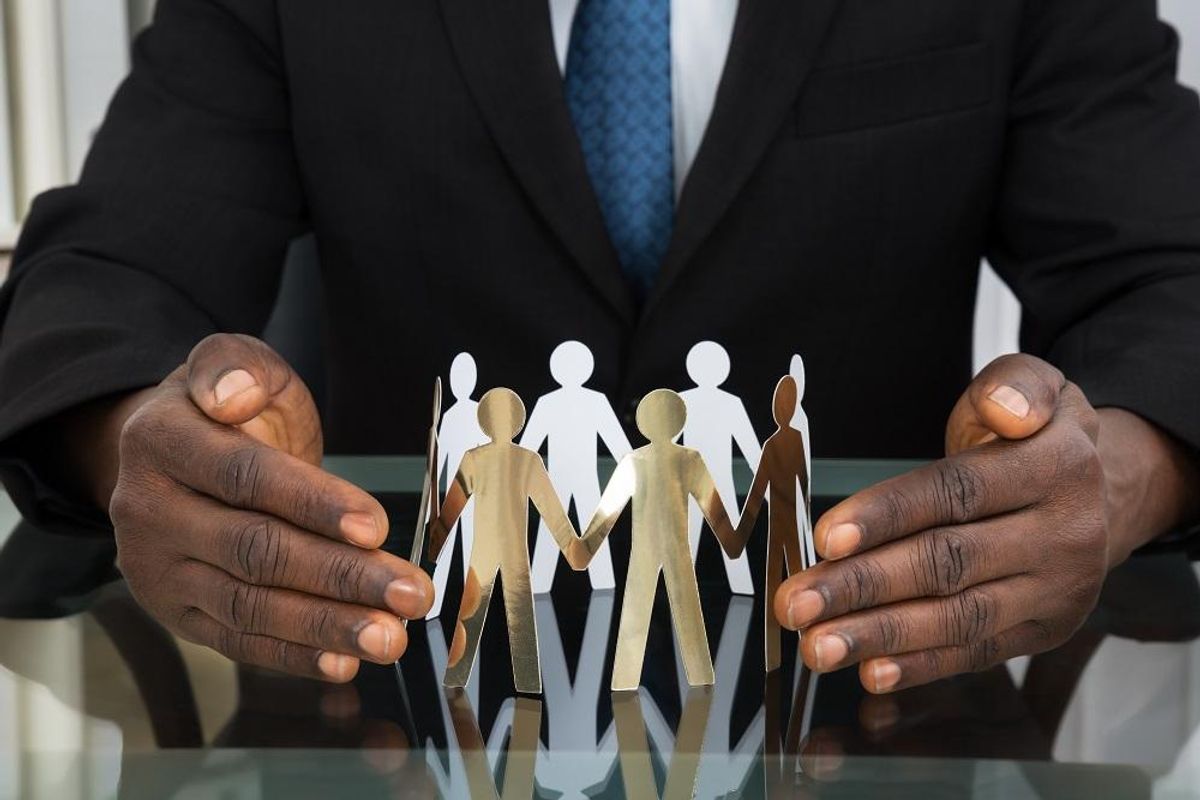 Businessman Protecting Paper Cutout People
