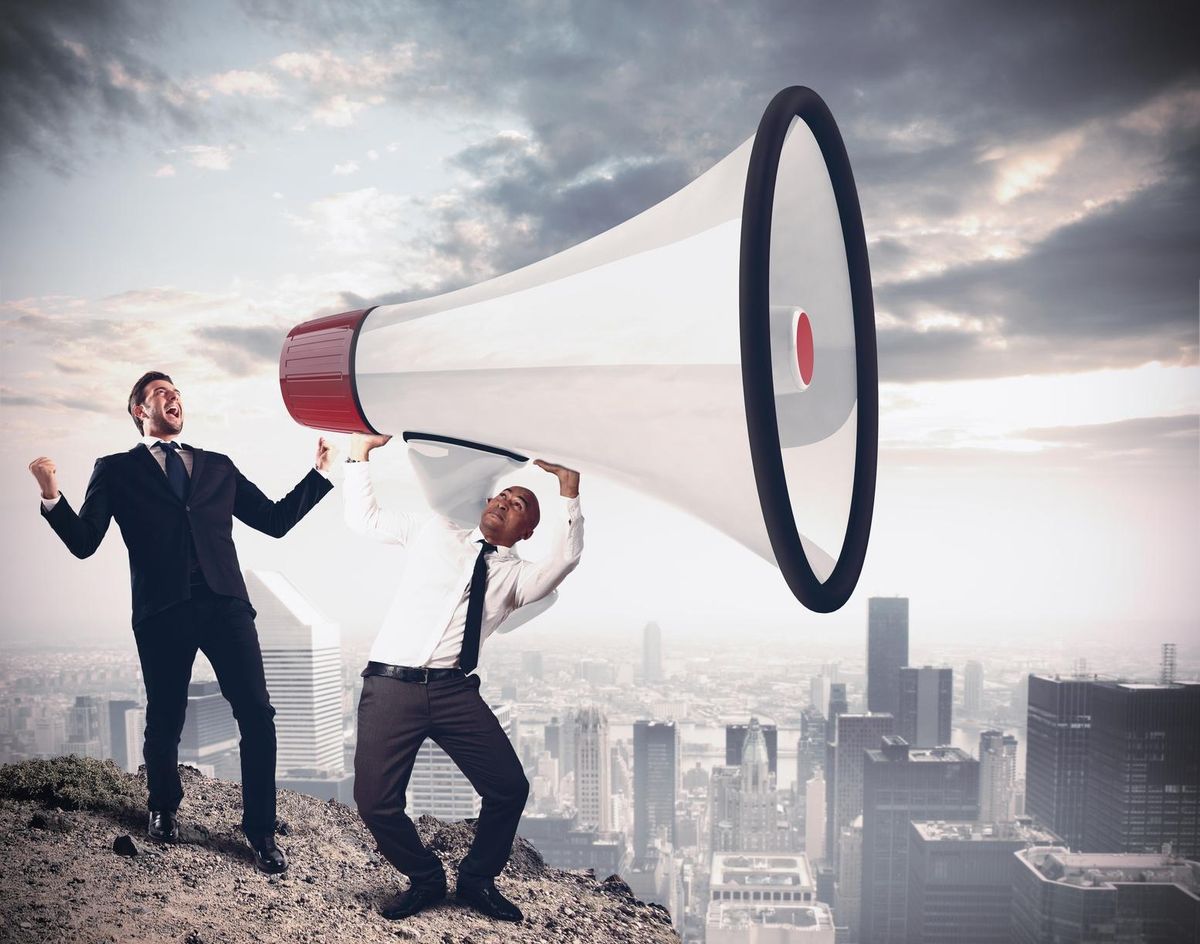 Businessman shouting into giant megaphone over the city