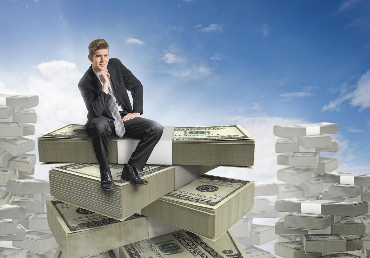 Businessman sitting on a stack of money