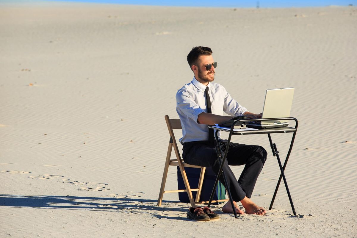 Businessman using laptop in a desert