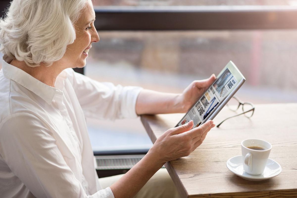 Cheerful senior woman reading news