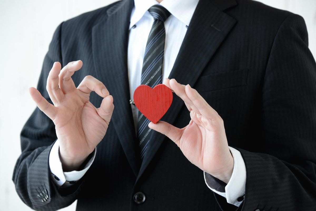 close-up of businessman with small red wooden heart