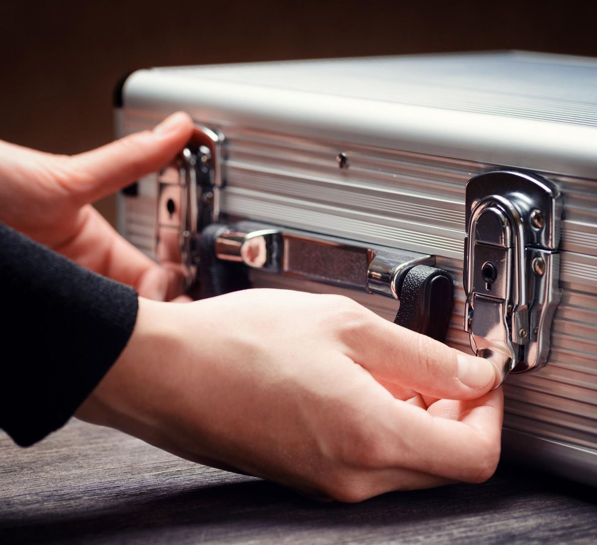 Close-up of male hands opening a brief-case