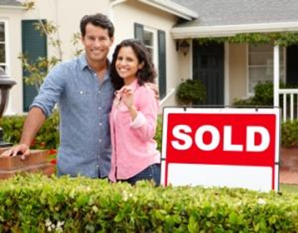 couple outside home with sold sign
