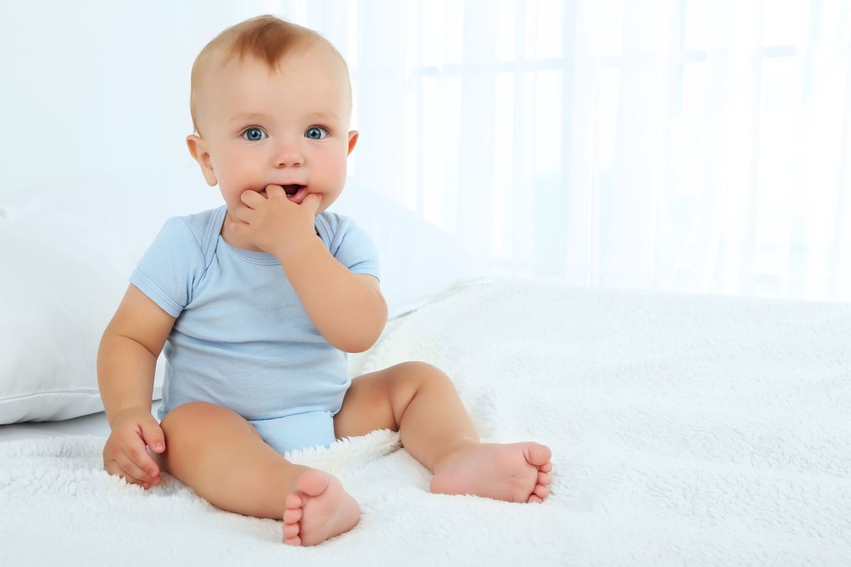 Cute baby boy on bed in room