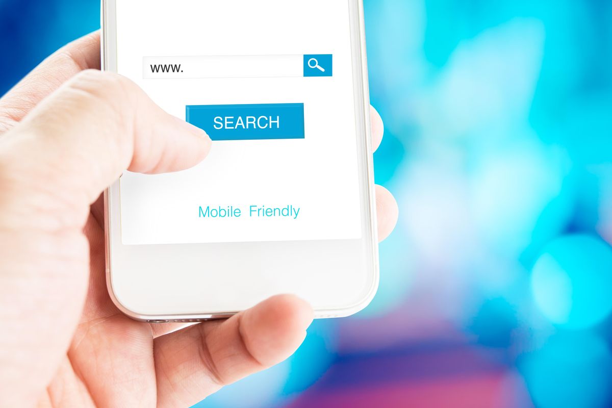 Hand holding mobile phone with search page on screen