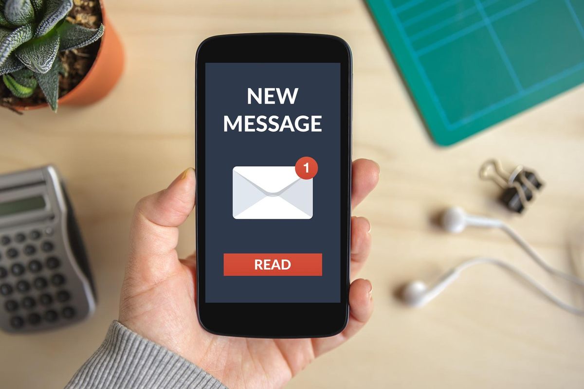 Hand holding smart phone with new message