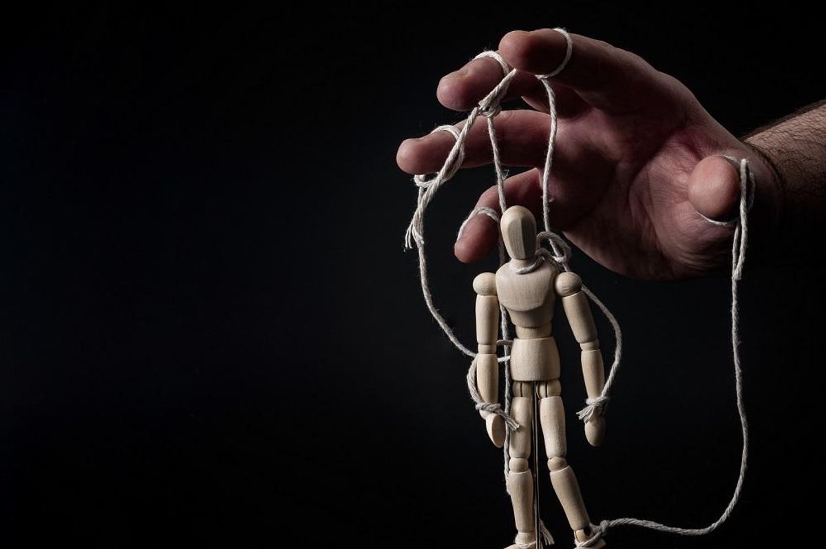 hand pulling the strings on a marionette