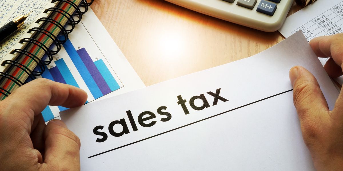 Hands holding documents with title sales tax