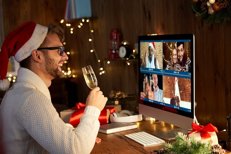Happy man wears santa hat celebrating during a remote holiday party.