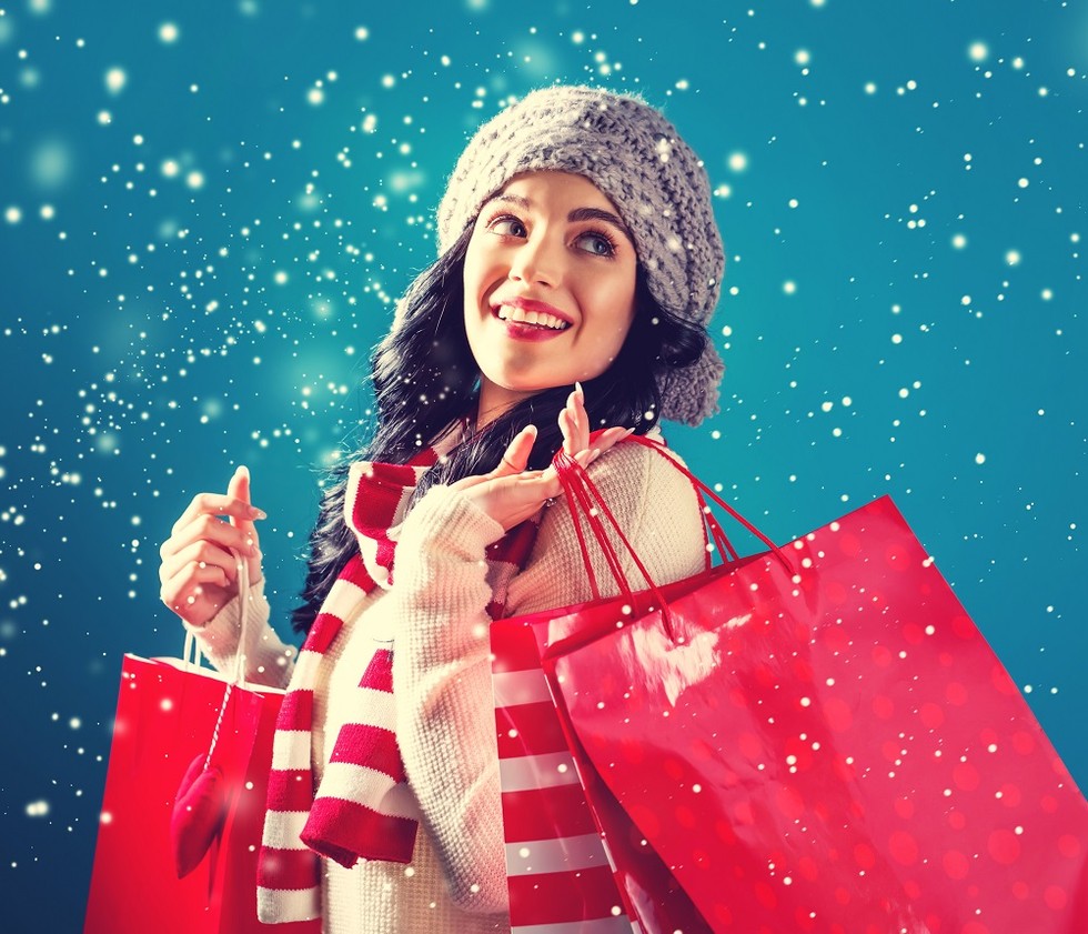 Happy young woman holding holiday shopping bags