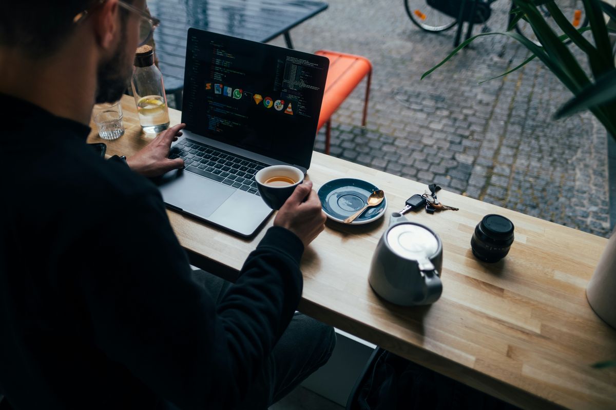 Man works on his side hustle from a coffee shop