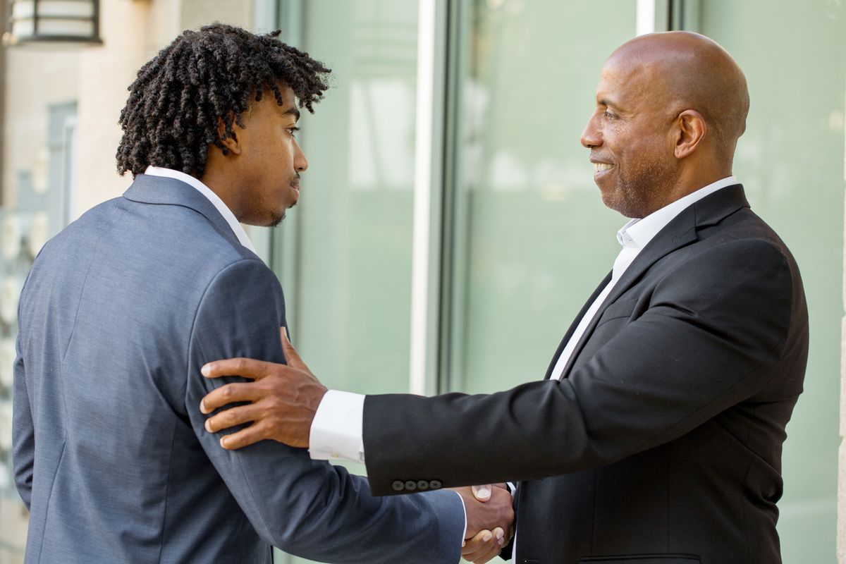 Mature businessman mentor shaking hands with his mentee