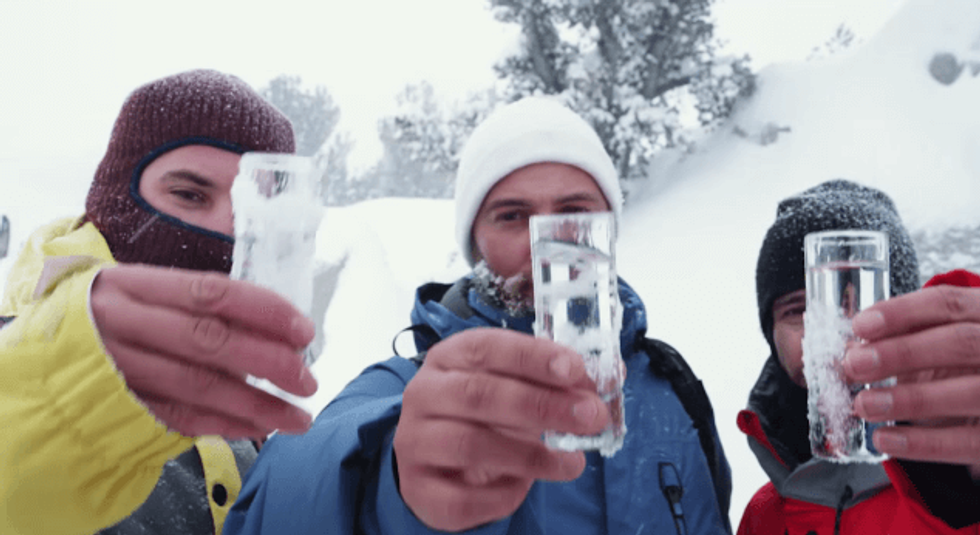 men holding up vodka drinks