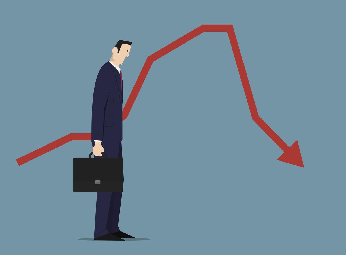 Sad businessman standing near sales chart
