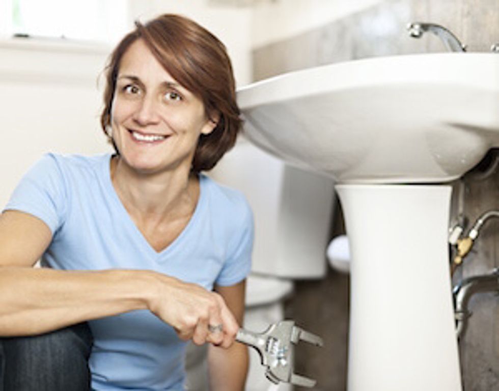 save money on rent: woman fixing plumbing
