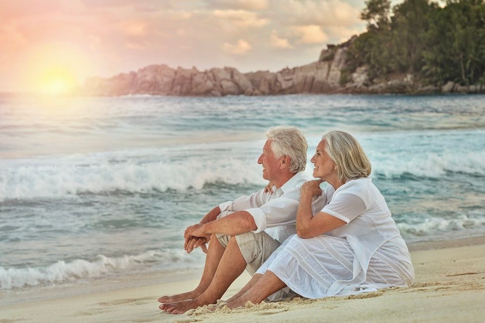 senior couple on beach, happy because of their retirement investment