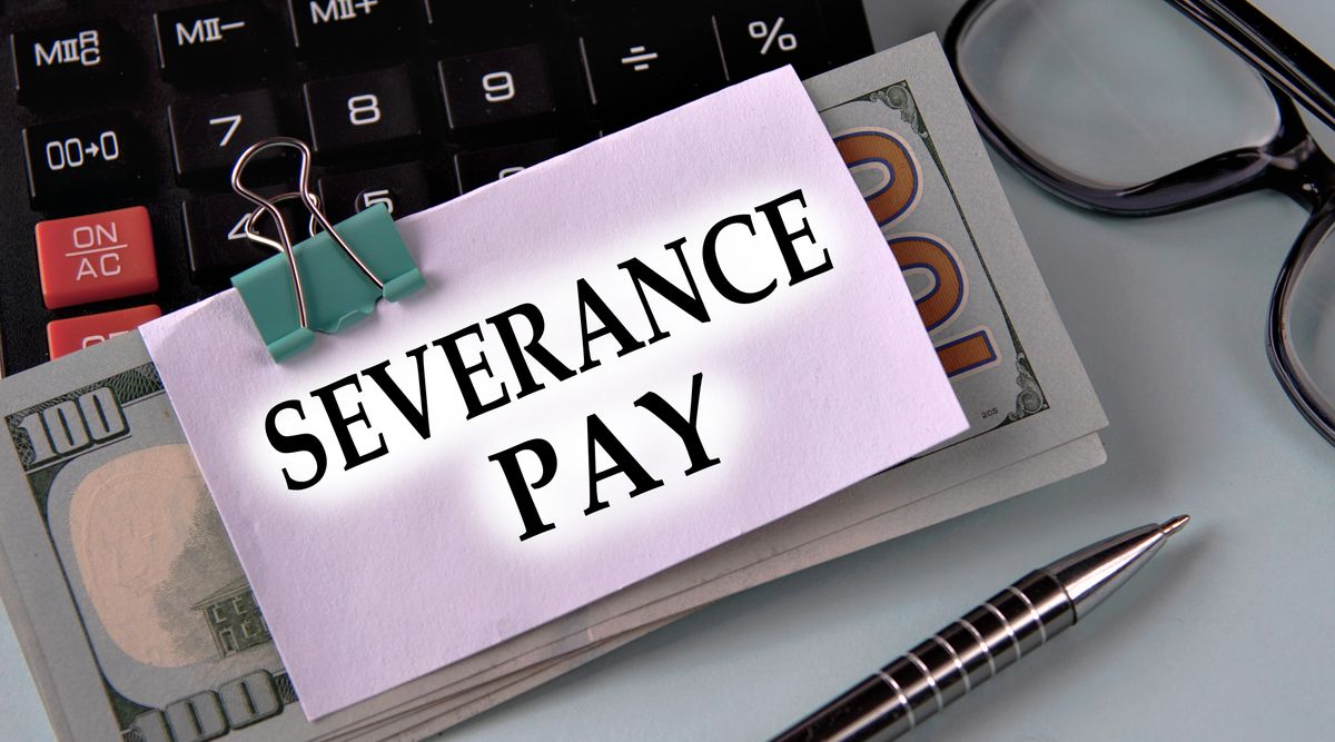 SEVERANCE PAY - words on a white piece of paper fixed on banknotes against the background of a calculator, glasses and pen