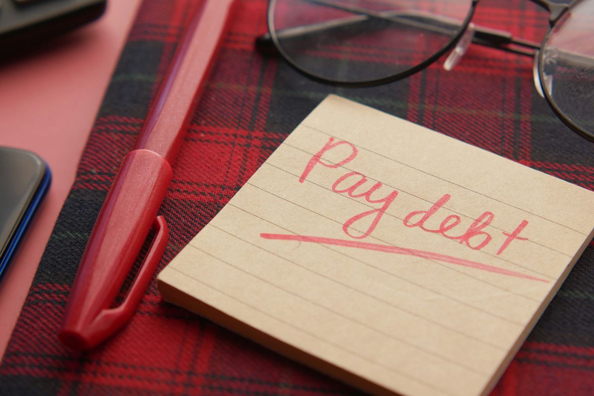 Sticky note with message to pay debt