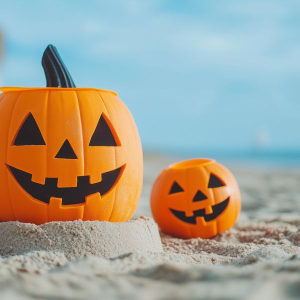 Summerween jack-o'-lanterns on sandy beach under clear sky
