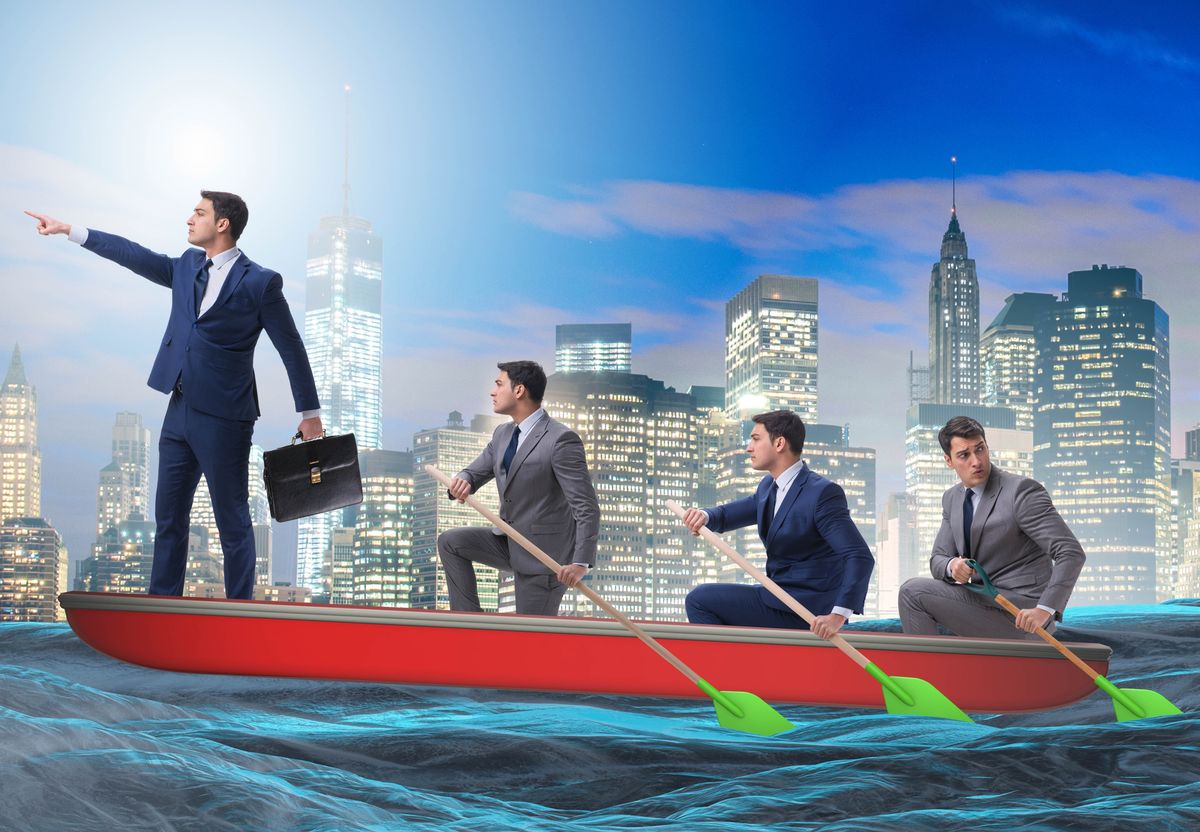 Team of businessmen rowing a boat toward a shared vision
