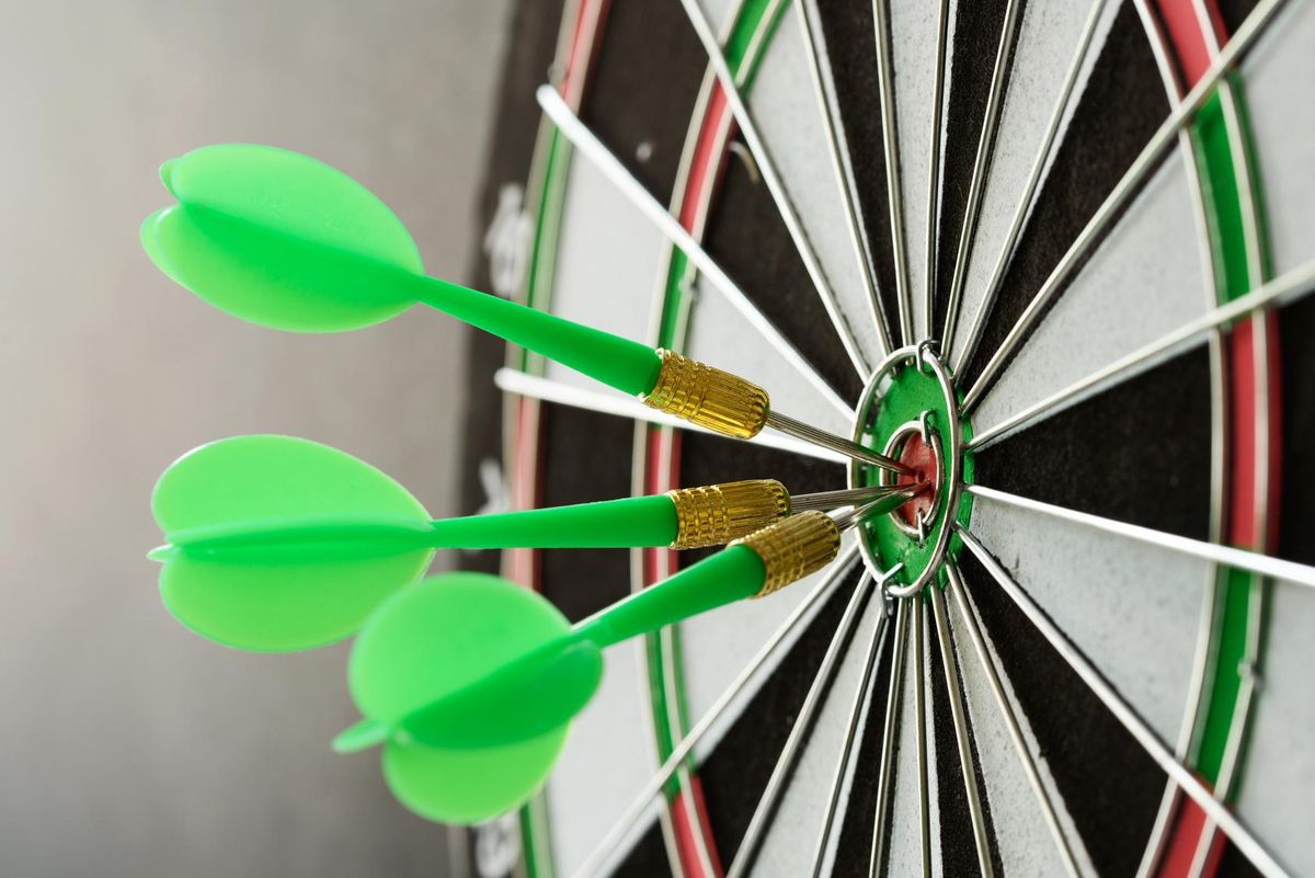 Three green darts pinned on the center of dartboard