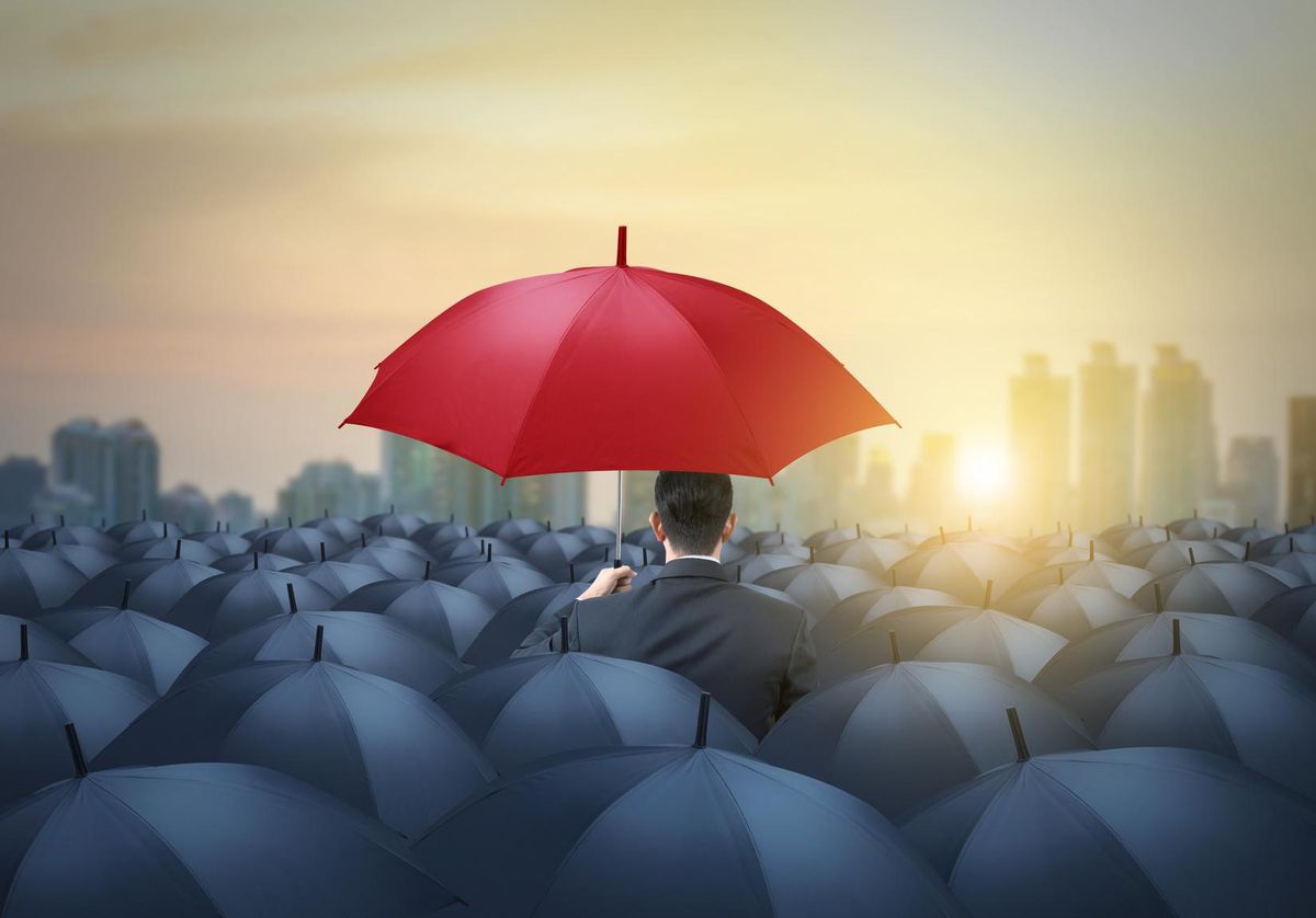 unique red umbrella among black umbrellas