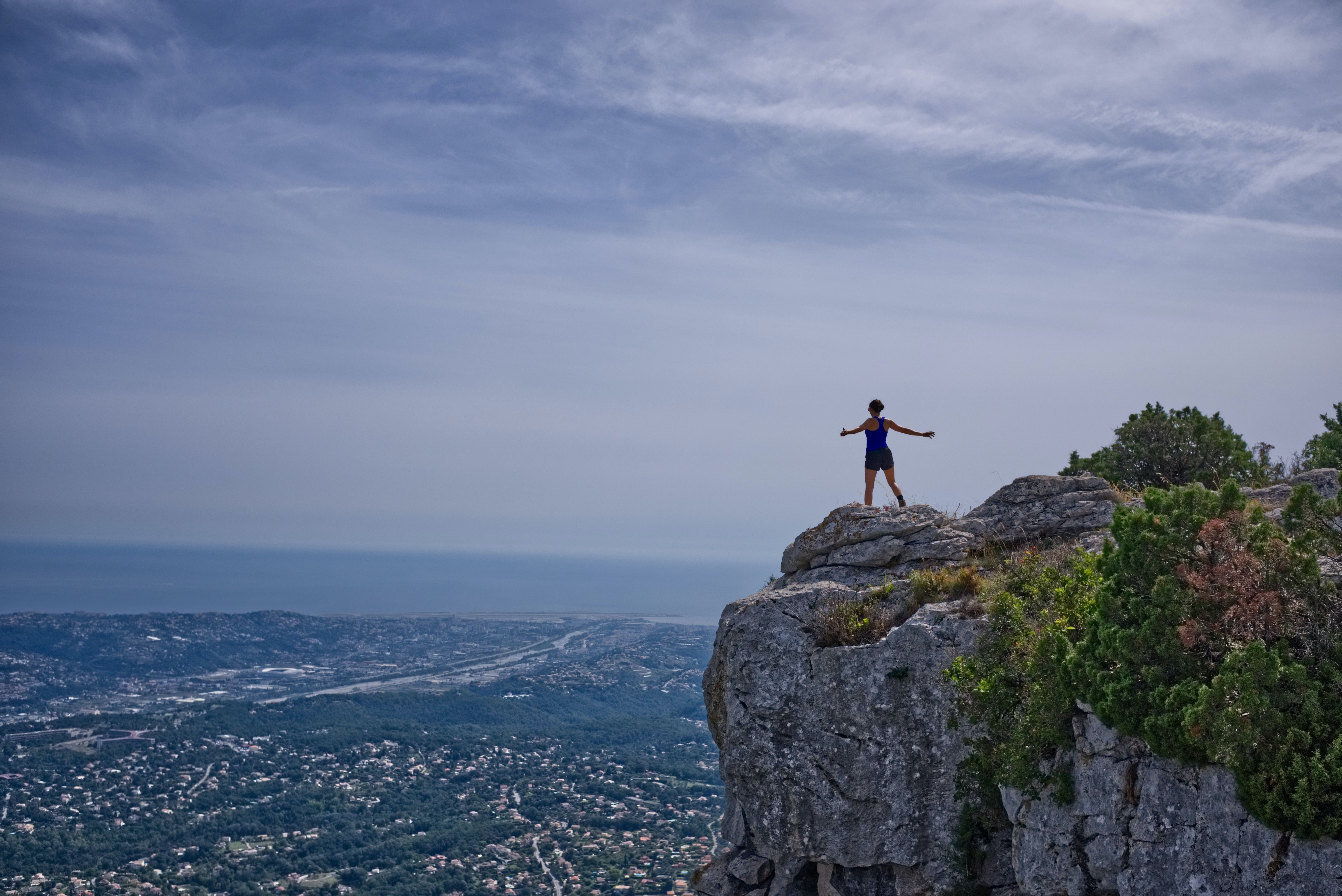 woman achieves business goals and stands atop cliff