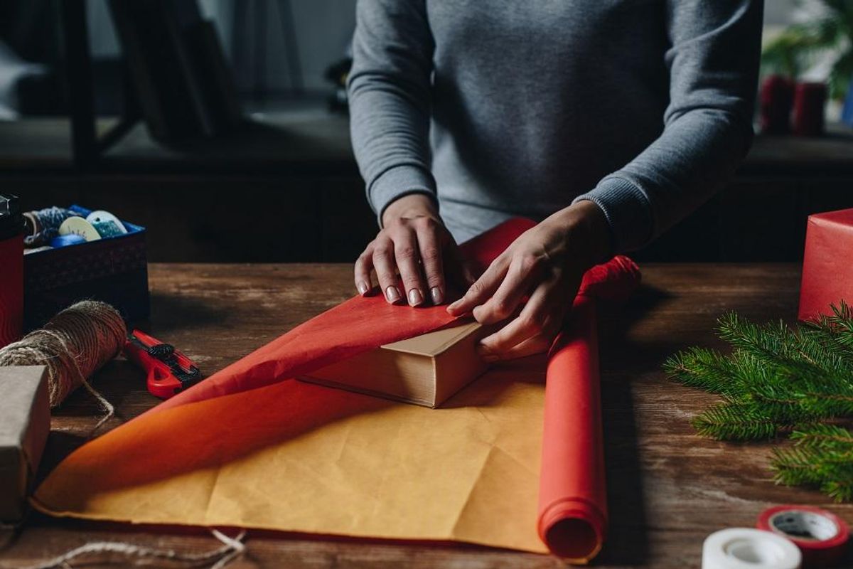woman wrapping book as Christmas gift
