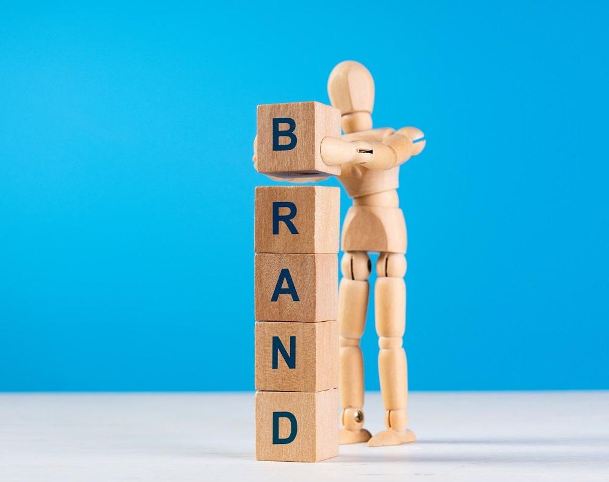 Wooden man construct tower with blue word BRAND