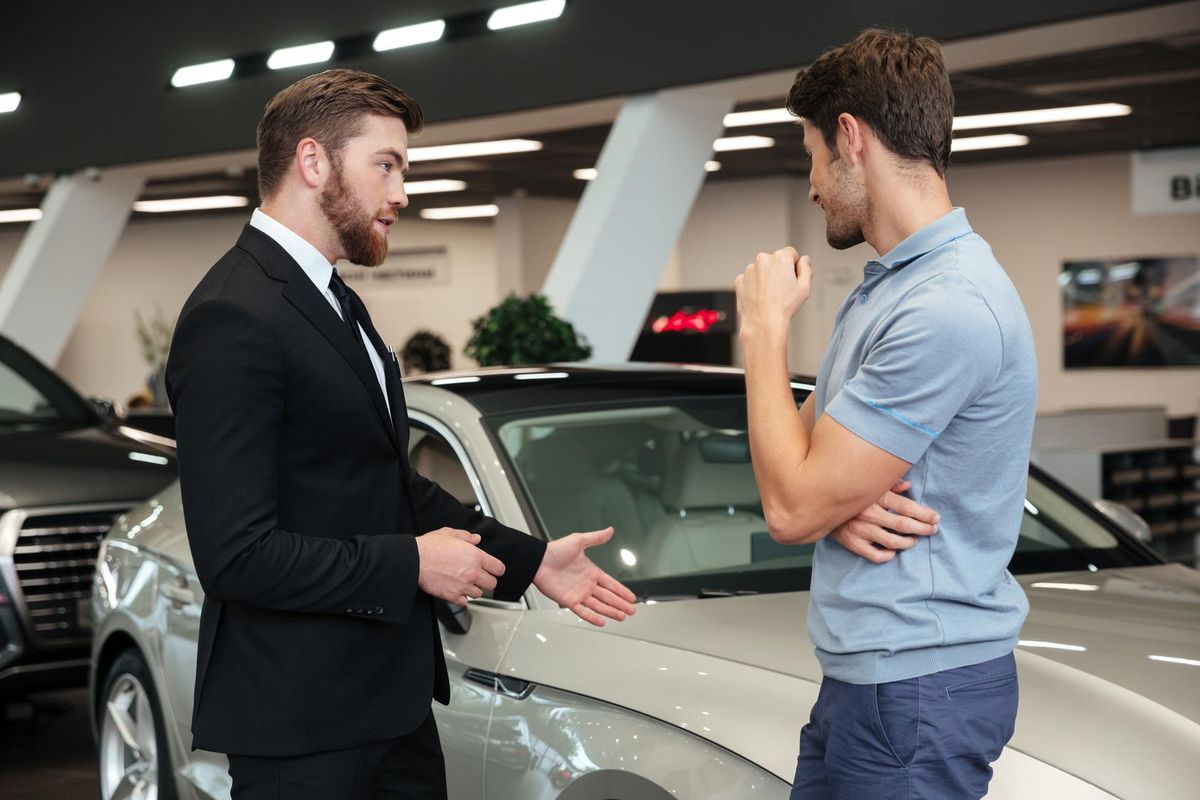 young car salesman showing a new car