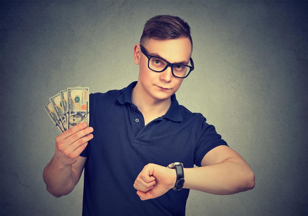 Young man holding money checking time