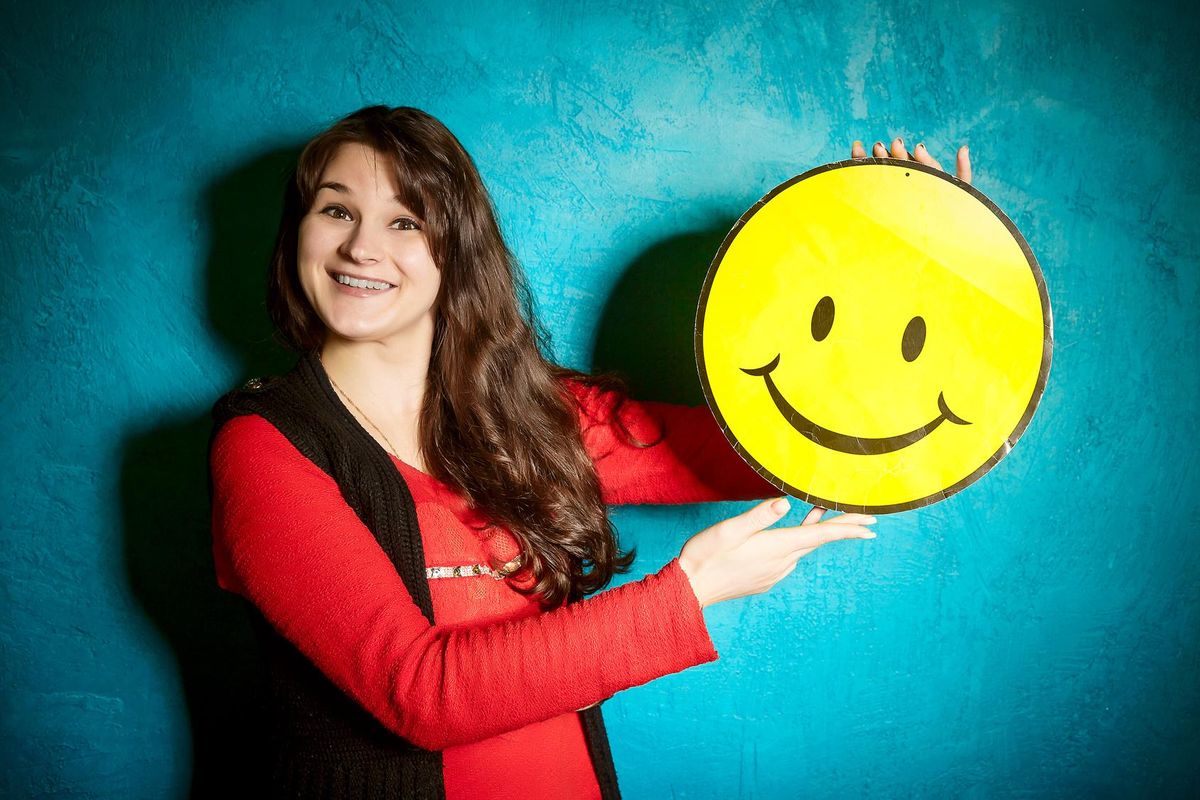 young woman holding a big yellow smiley