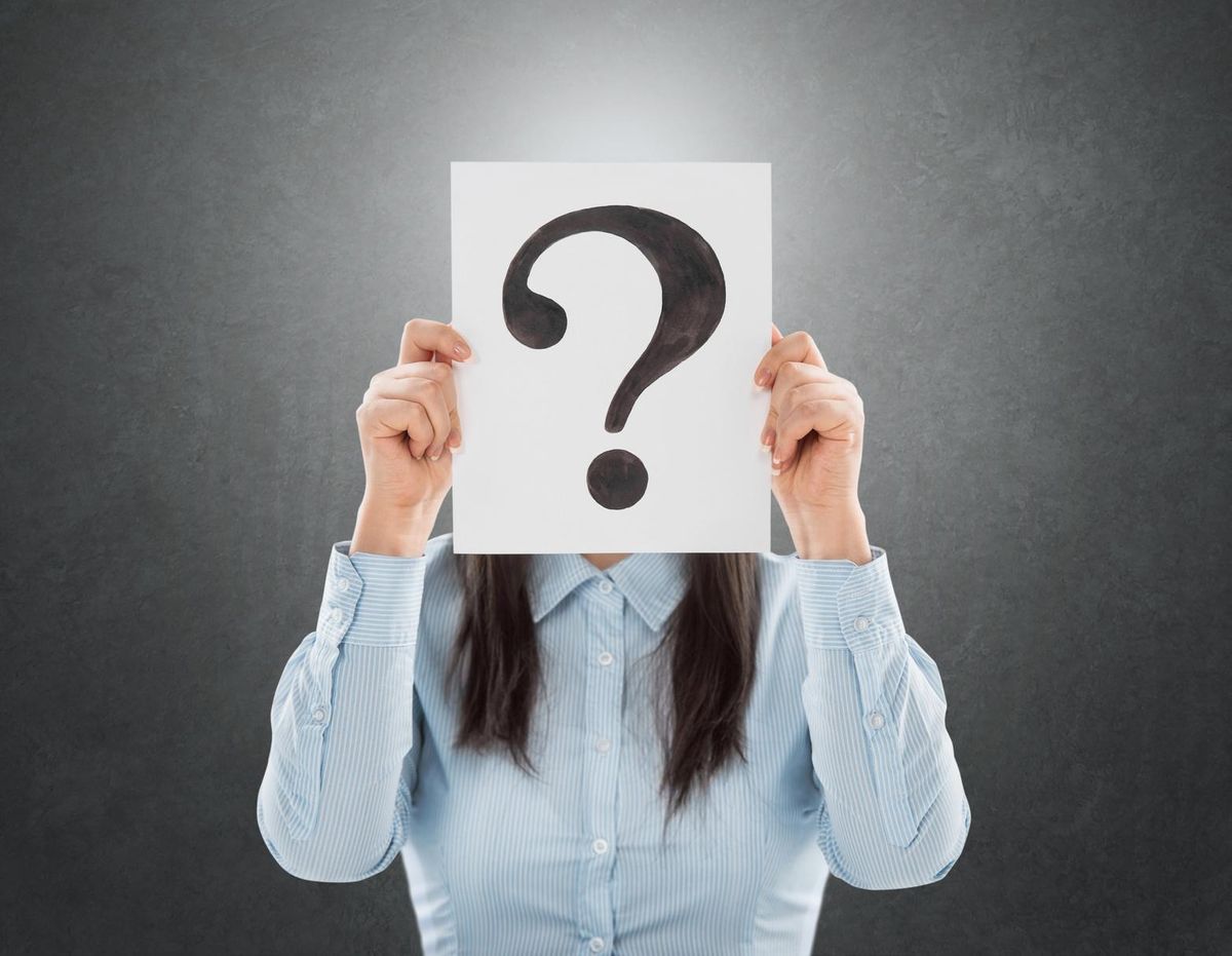Young woman holding question symbol in front of her face